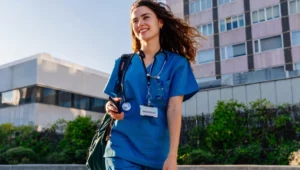 Médica sorridente usando uniforme azul com estetoscópio.