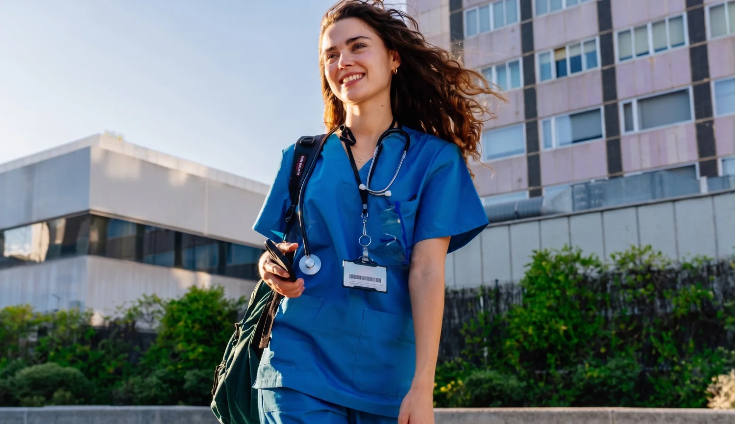Médica sorridente usando uniforme azul com estetoscópio.