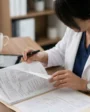 Médica analisando documentos de saúde em mesa de trabalho.
