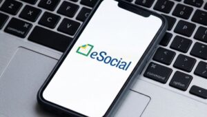 Logotipo do eSocial em smartphone sobre teclado preto.