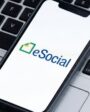 Logotipo do eSocial em smartphone sobre teclado preto.