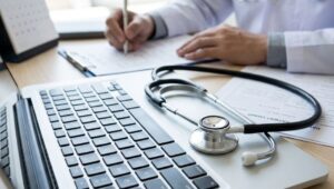Mão de médico escrevendo ao lado de um estetoscópio