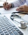 Mão de médico escrevendo ao lado de um estetoscópio